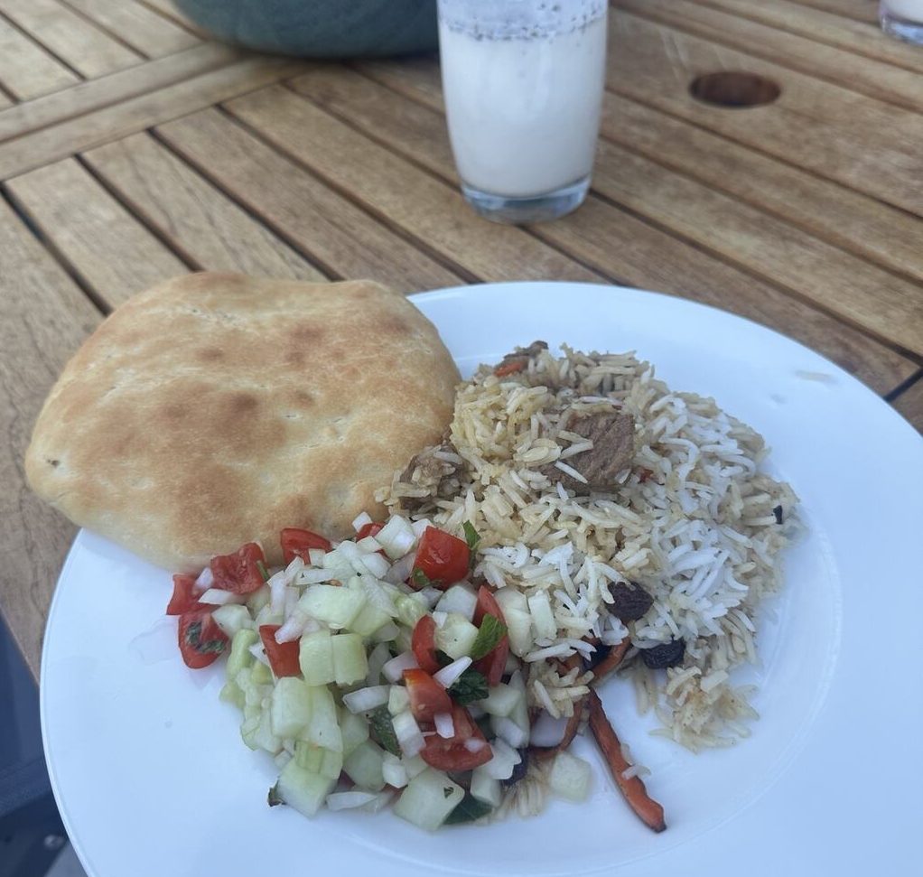 A plate of Kabuli Palaw, fresh salata and homemade naan with a glass of doogh.